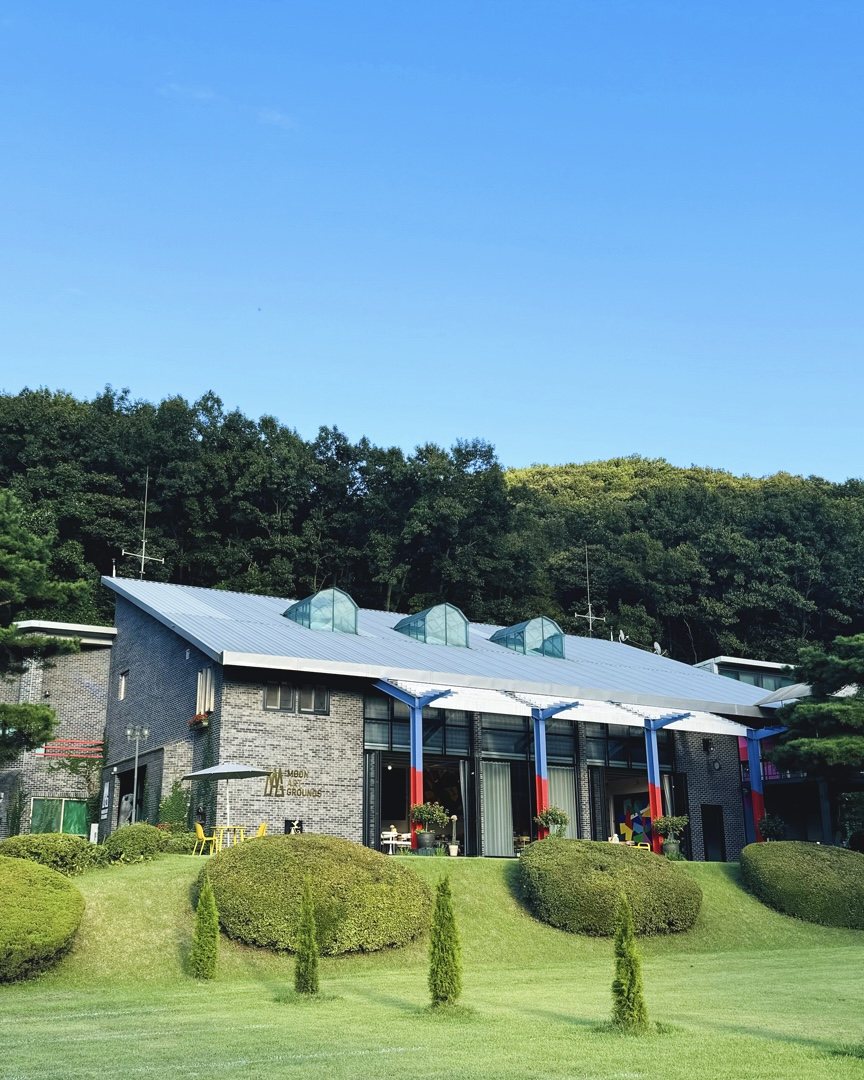 The Moon Art Grounds museum building near Seoul, with a sawtooth skylight roof set against a wooded hillside